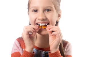 girl holding oral appliance to mouth